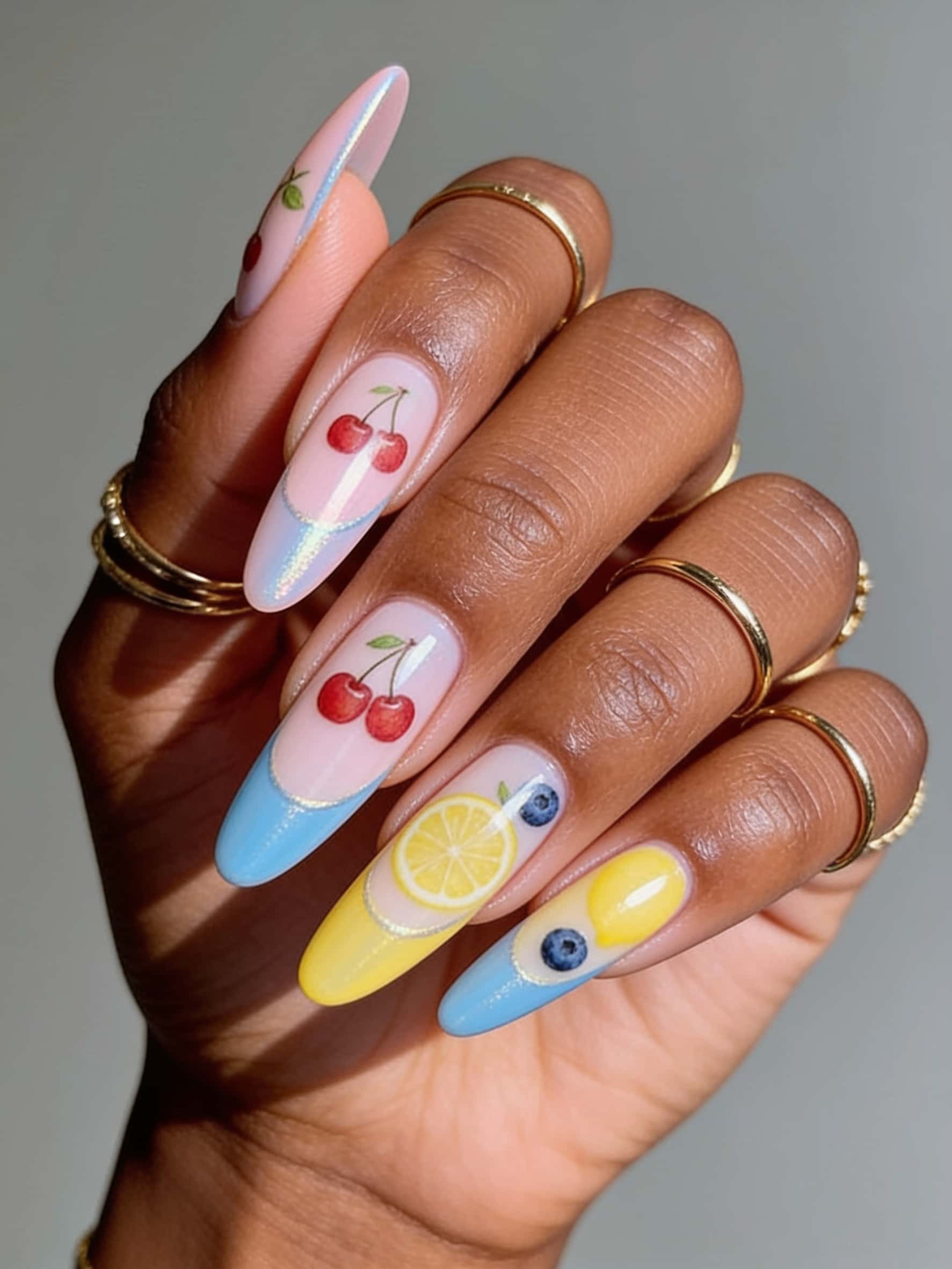 Almond-shaped nails with French tip design featuring glitter line and colorful fruit art in shades of blue, lemon, and cherries.