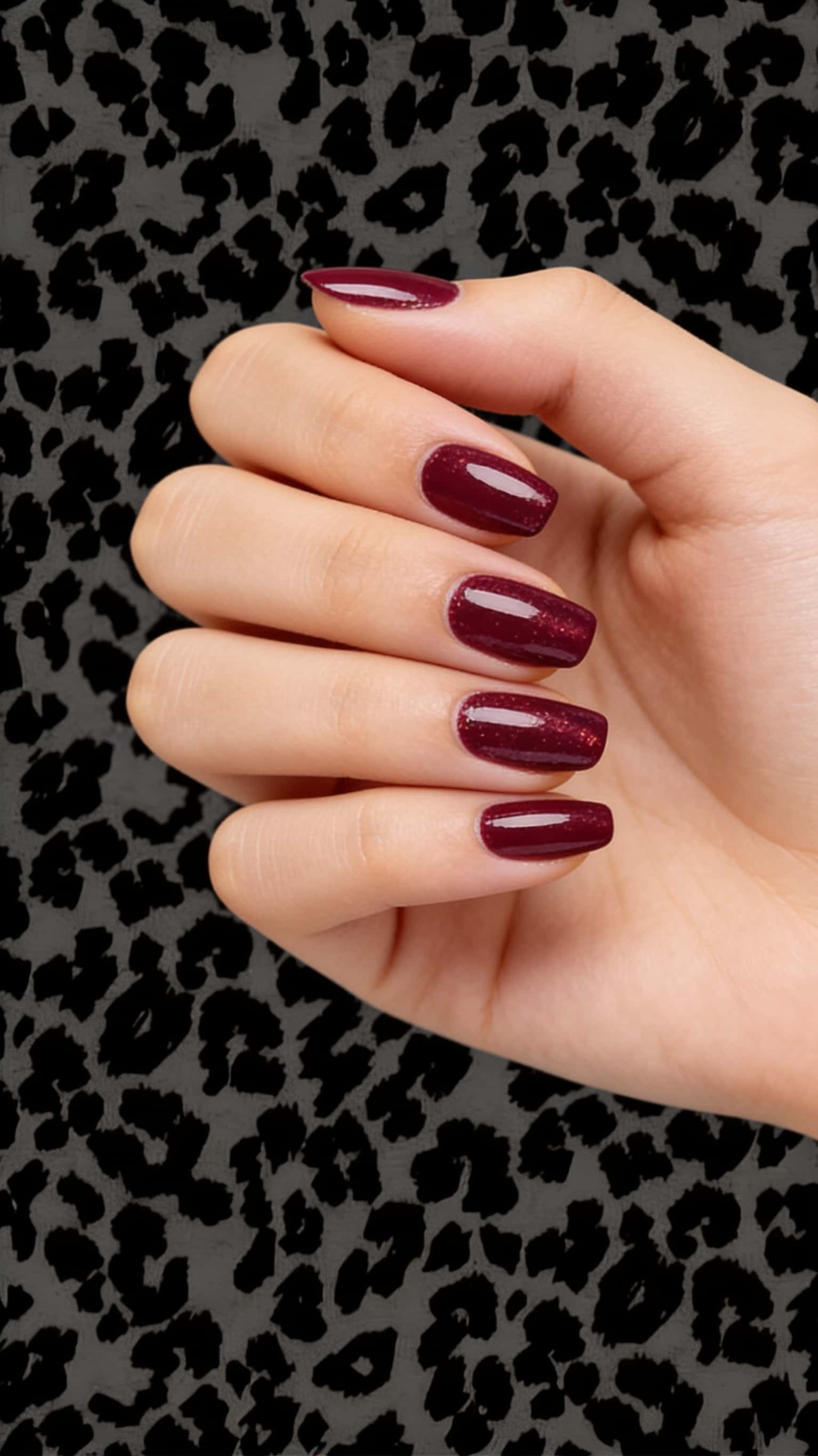 Medium oval nails featuring a deep burgundy glitter polish with a glossy finish.