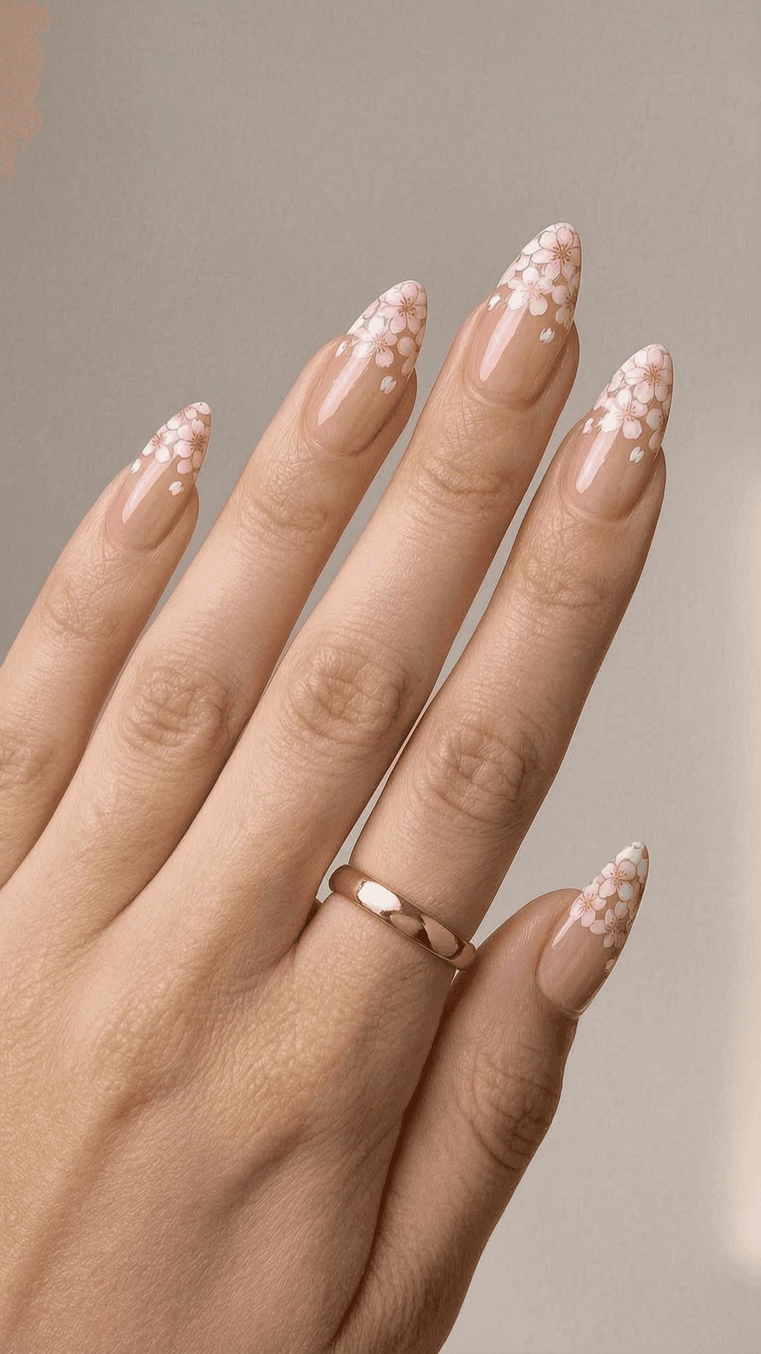 Long almond nails with a sheer nude base and pink and white cherry blossom floral French tips.