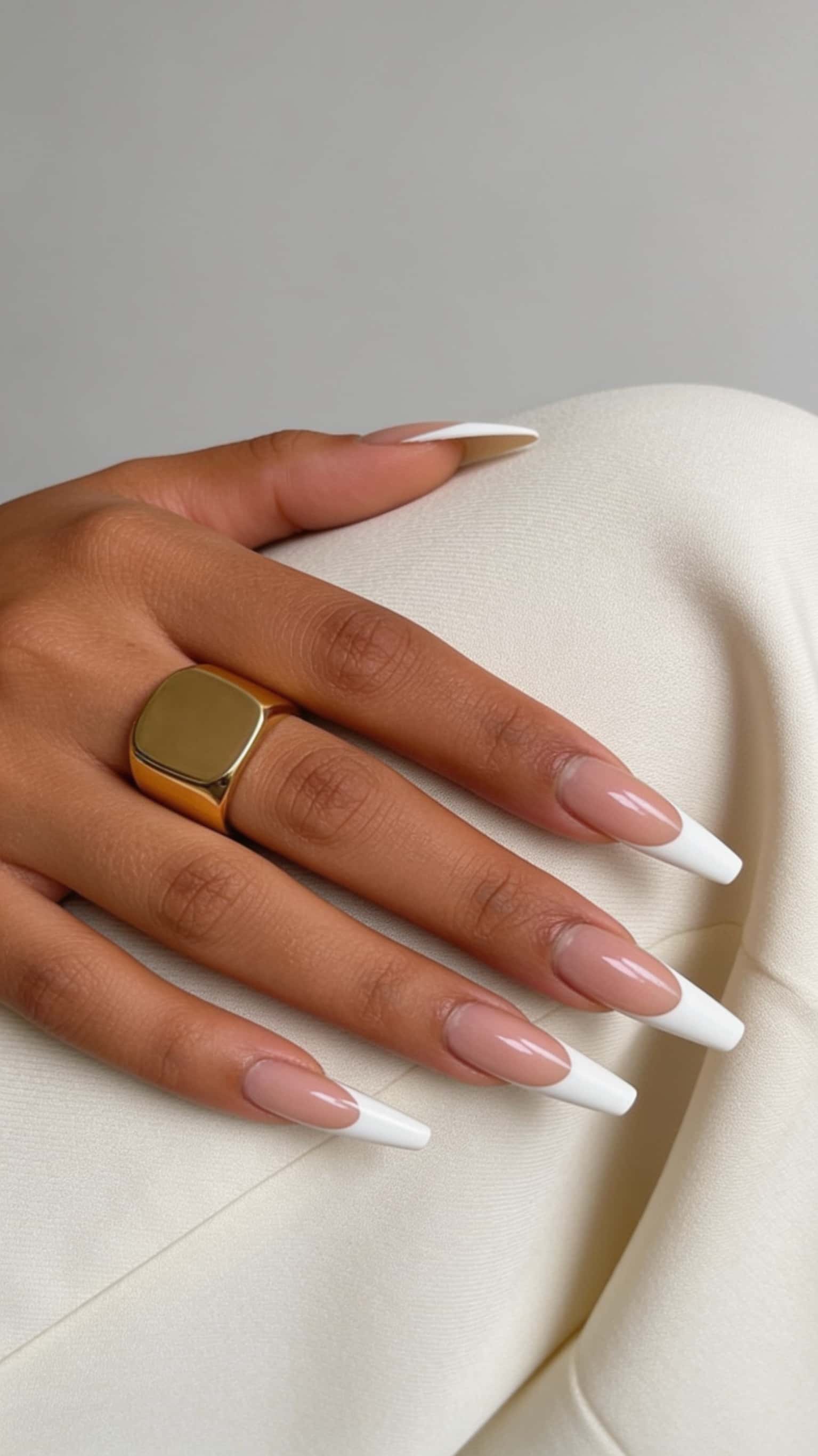 Long coffin nails with a classic French manicure featuring a nude base and white tips.