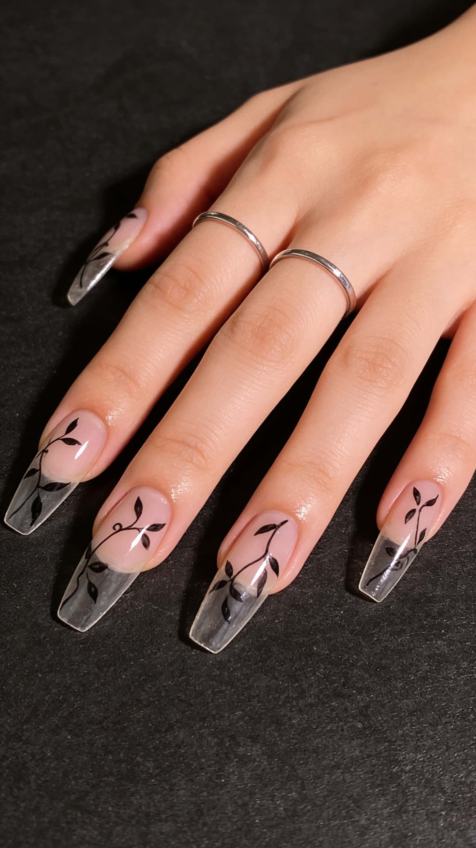 Long coffin nails with hand-painted floral design in nude and black, glossy finish.