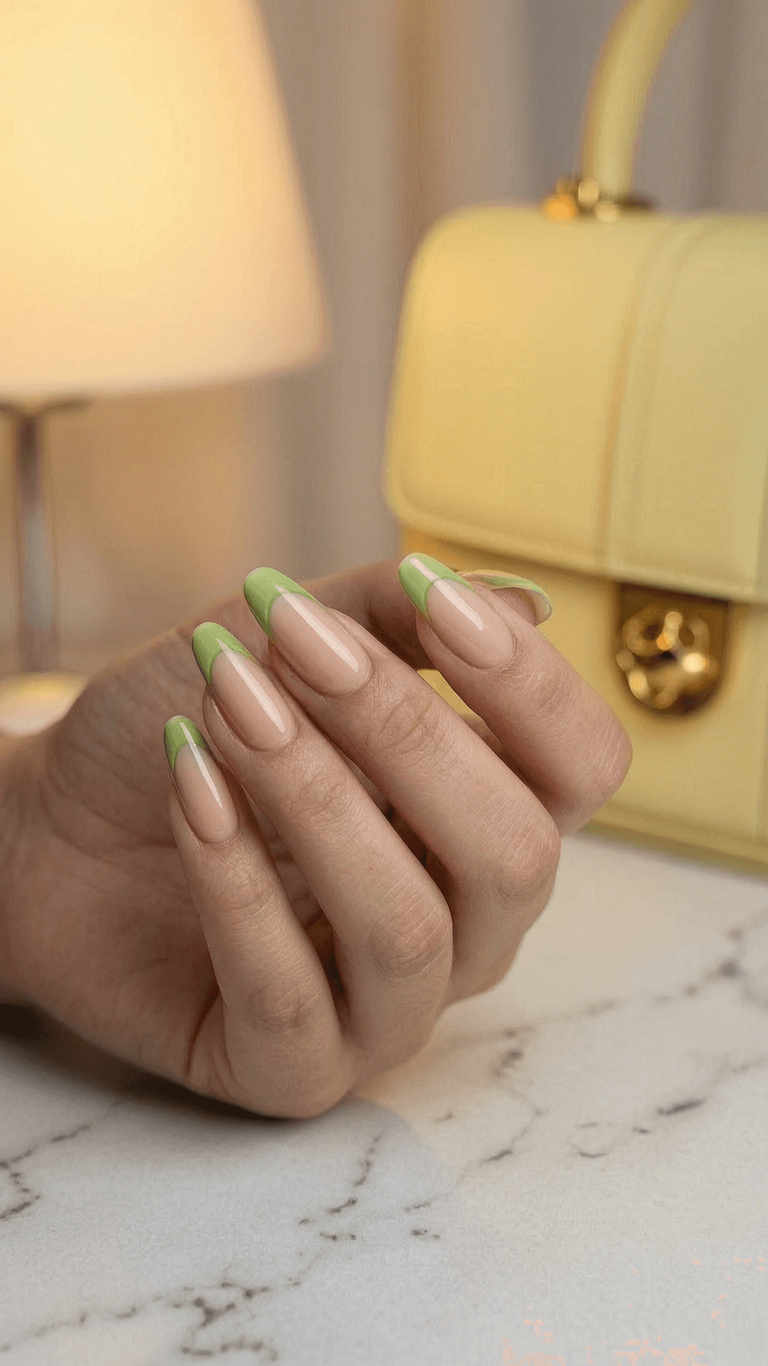 Almond-shaped nails with a green outline on a nude base.