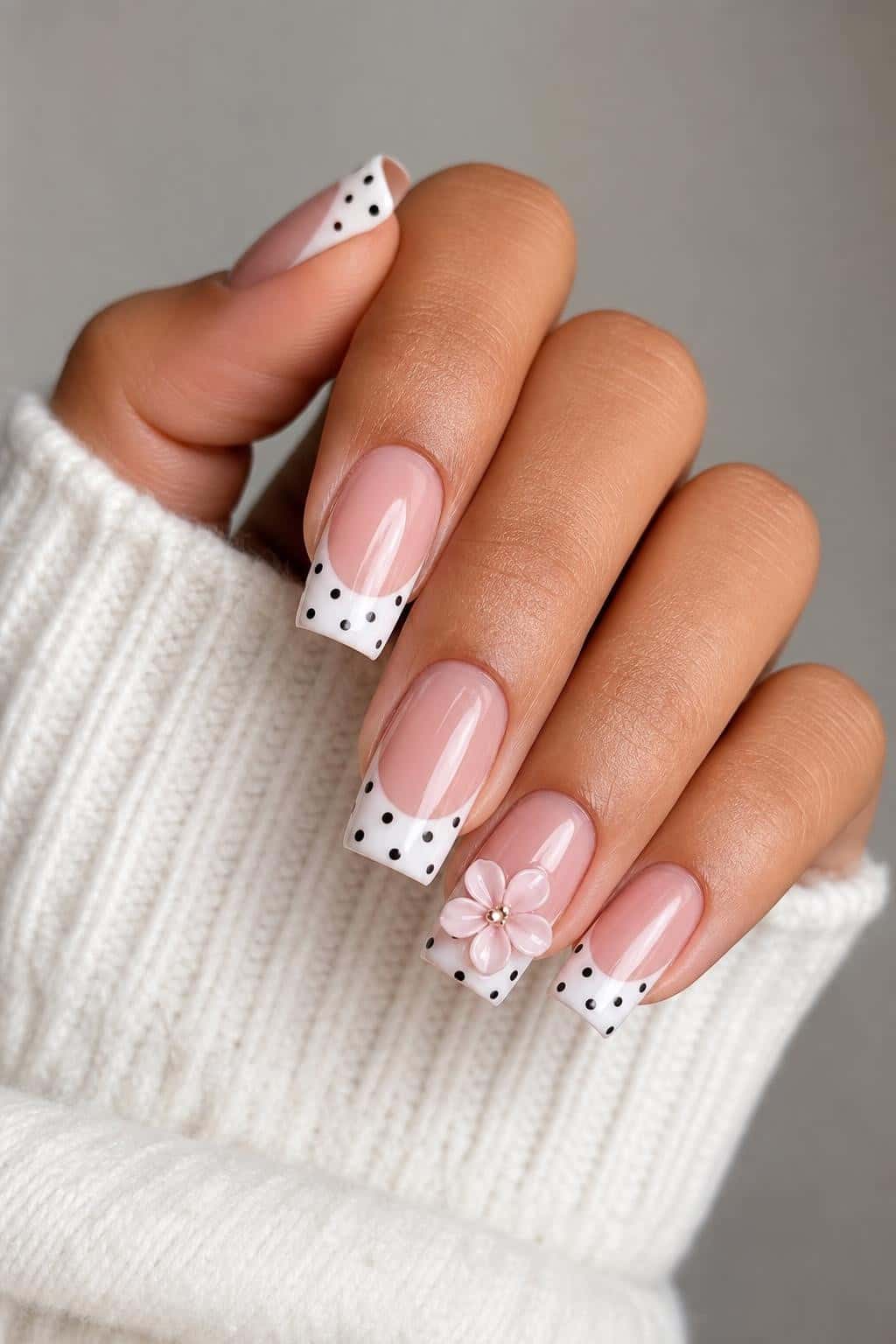 Long stiletto nails with nude base, glossy finish, and 3D flower polka dots.