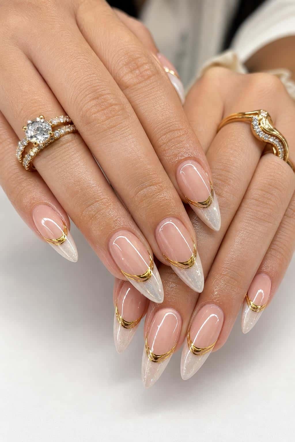 Long stiletto nails with a nude base and metallic accents.