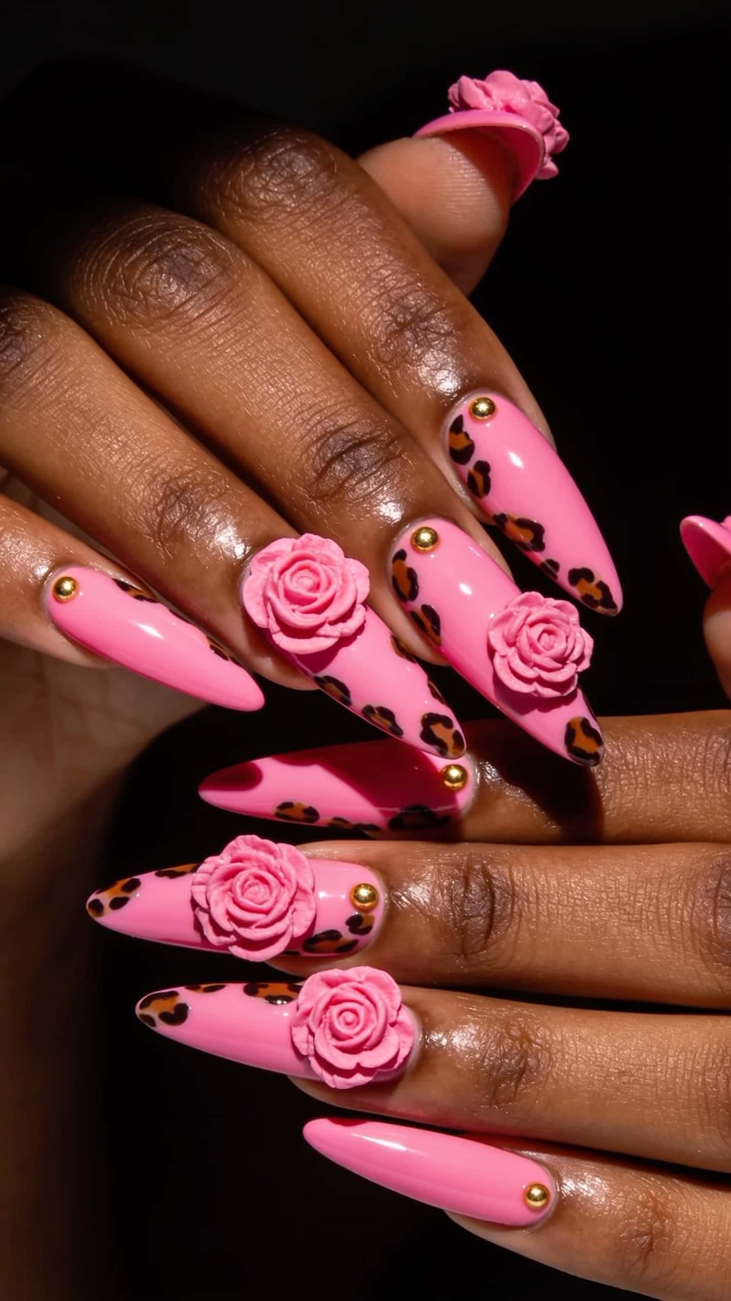 Long stiletto nails with a bright pink base, leopard print accents, 3D pink roses, and gold studs.
