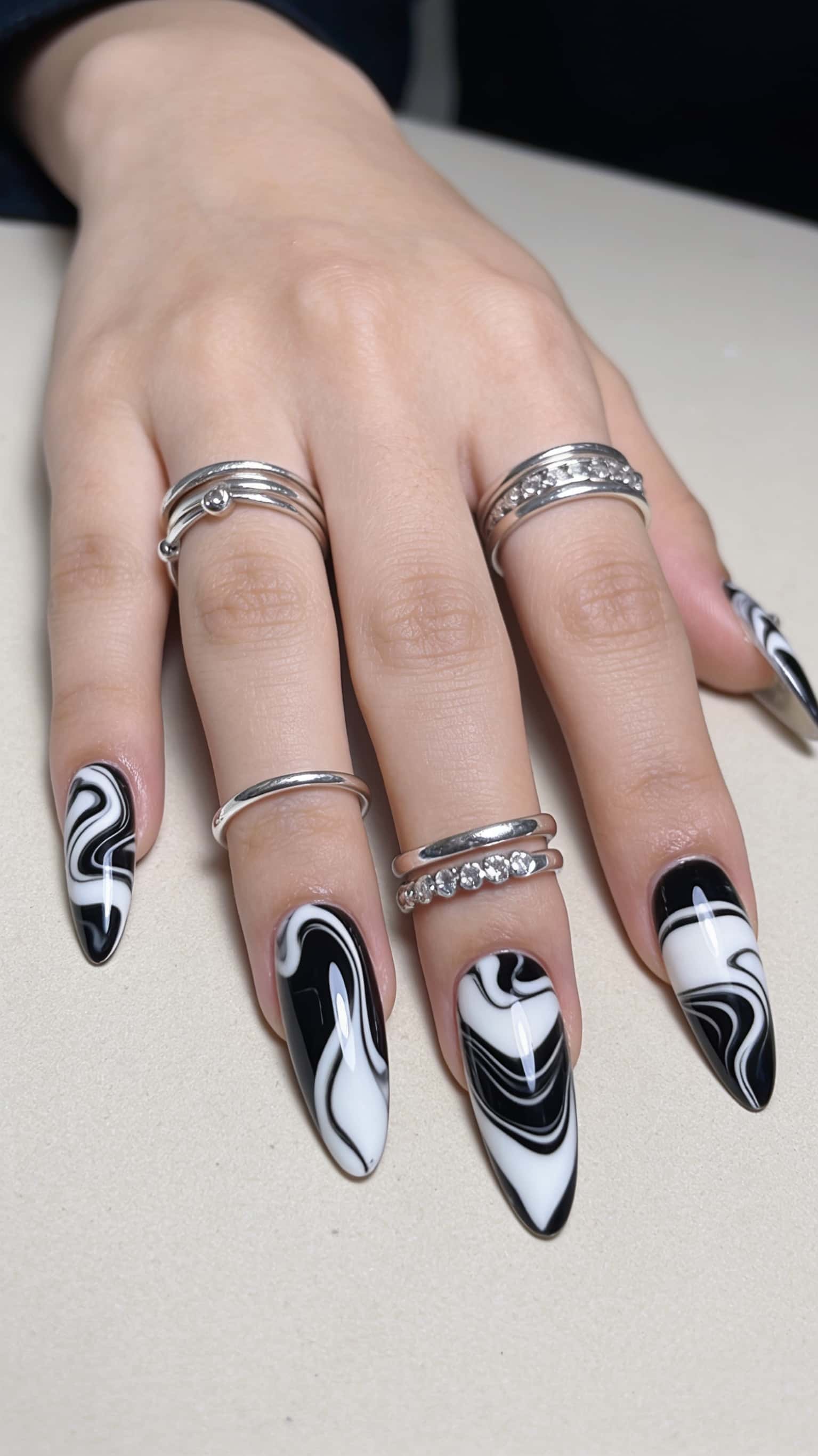 Long stiletto nails with a high-contrast black and white swirl pattern.
