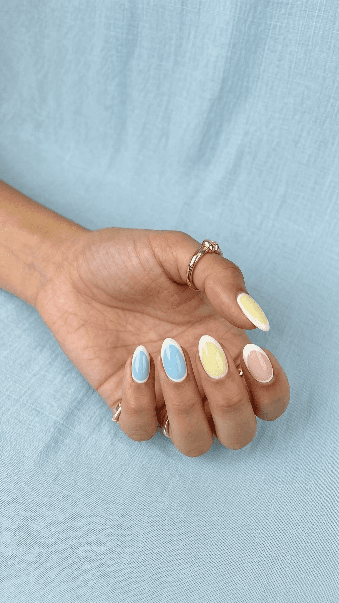 Short to medium oval nails feature a multi-color pastel design.