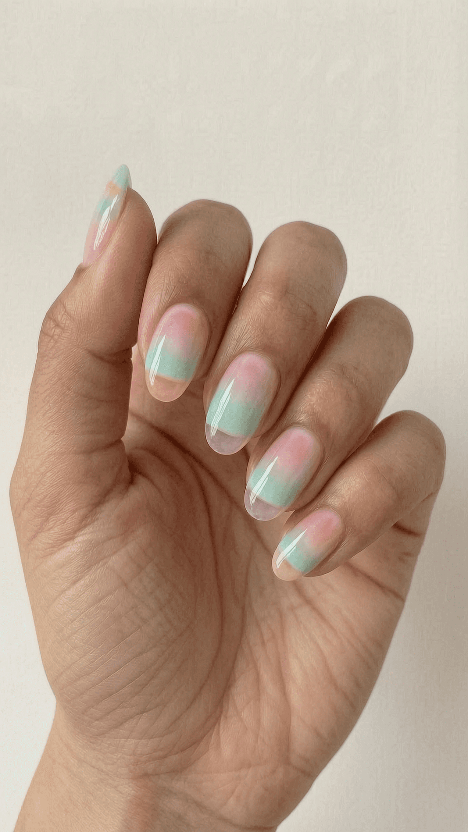 Oval nails with a soft pastel watercolor ombre in pink, green, and orange, featuring a translucent jelly finish.