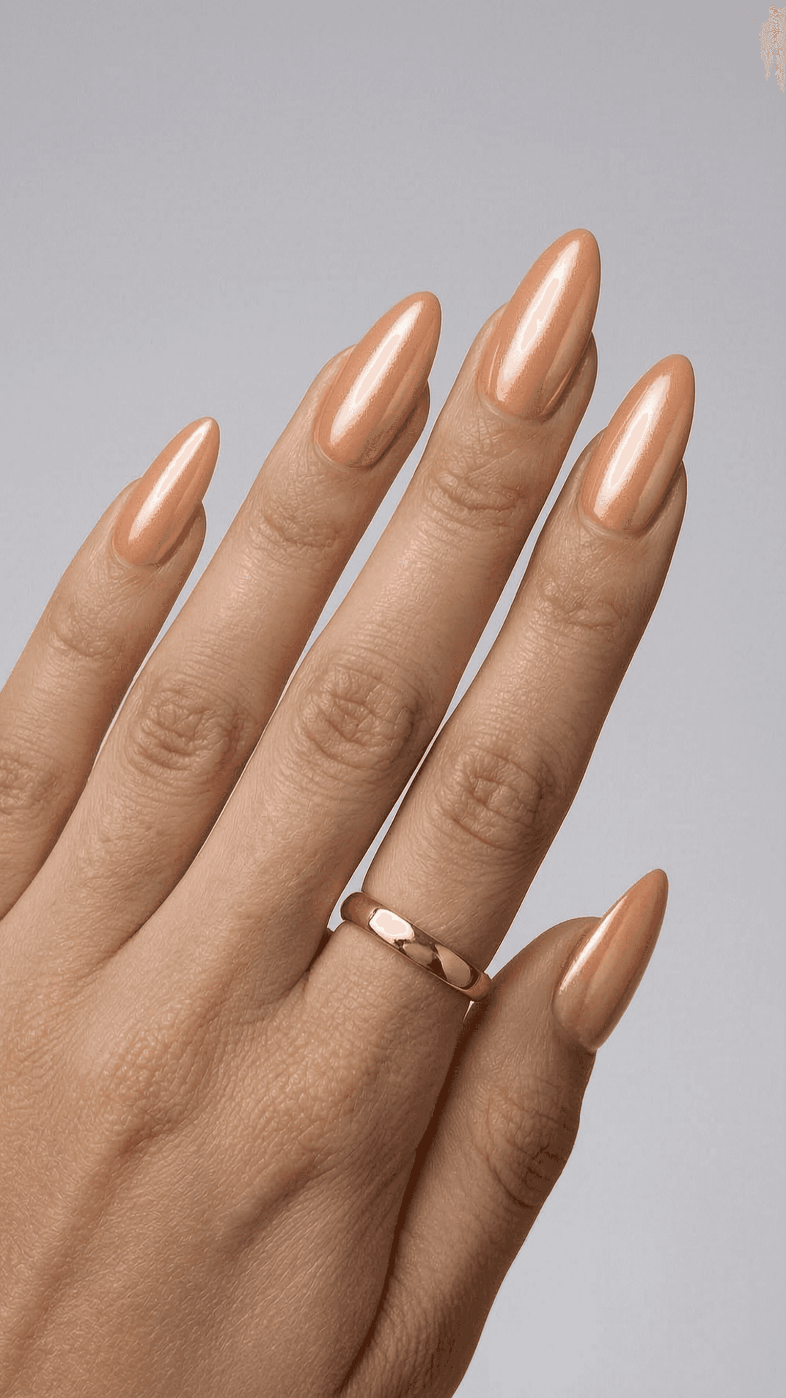 Long almond nails with a warm peach pearlescent shimmer and a high-gloss finish.