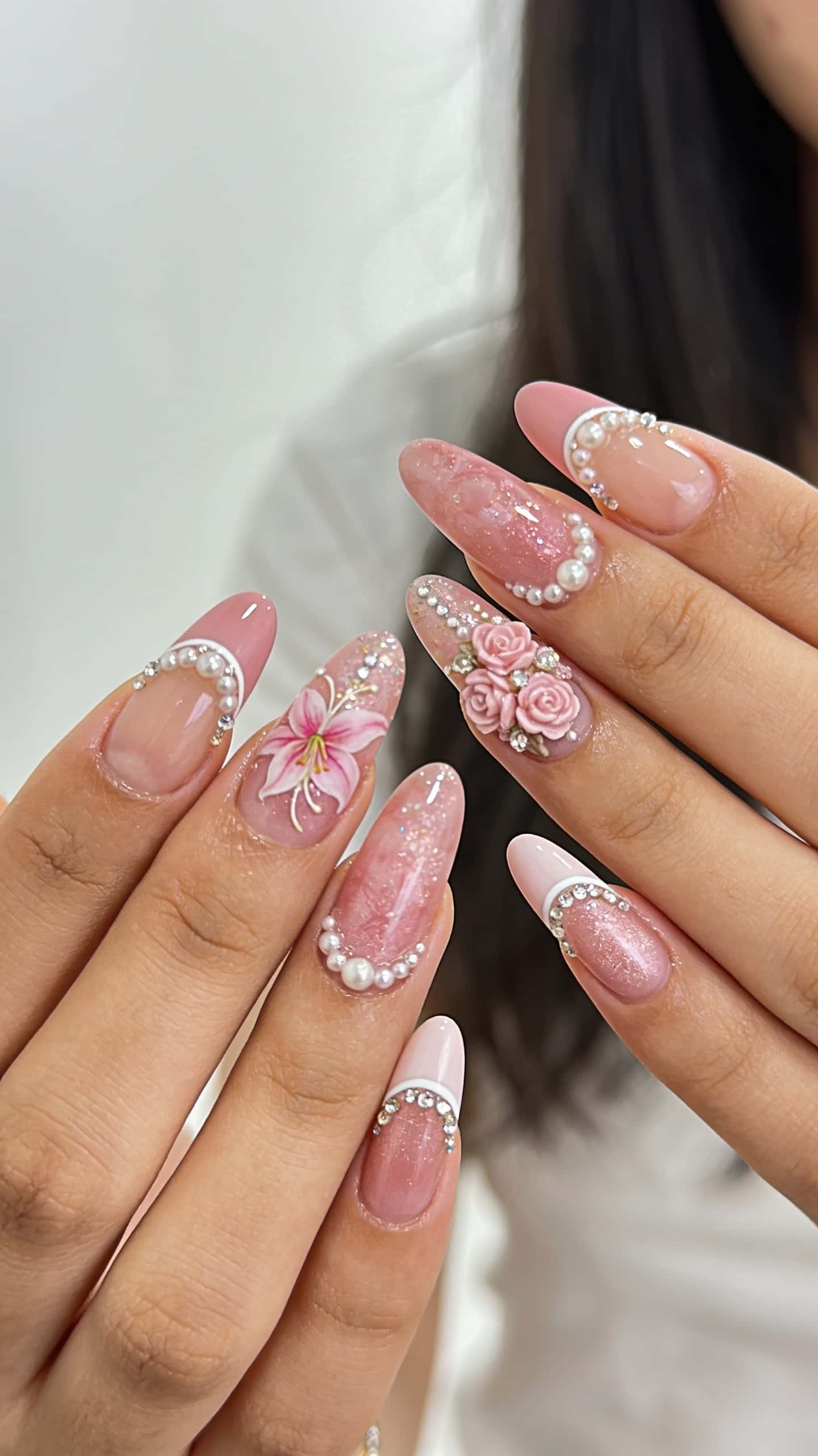 Long pink floral almond nails with glitter and rhinestones.