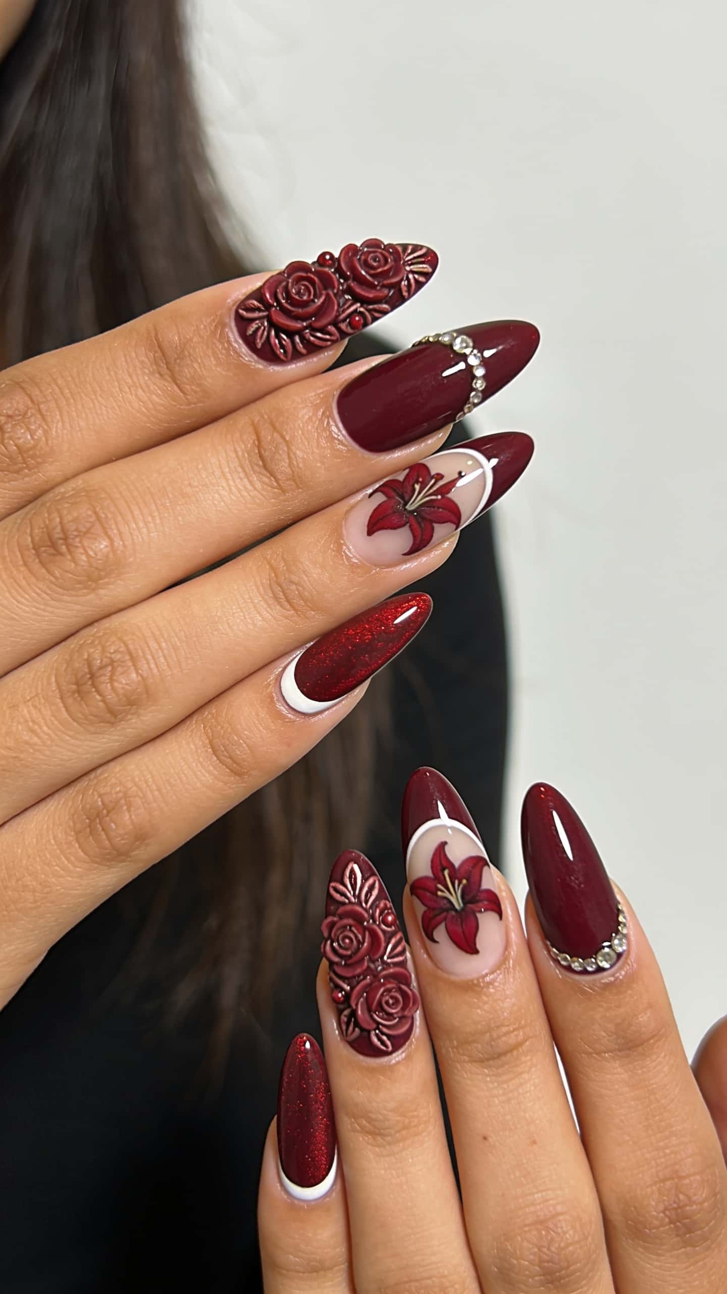 Long pink floral almond nails with glitter and rhinestones accents.