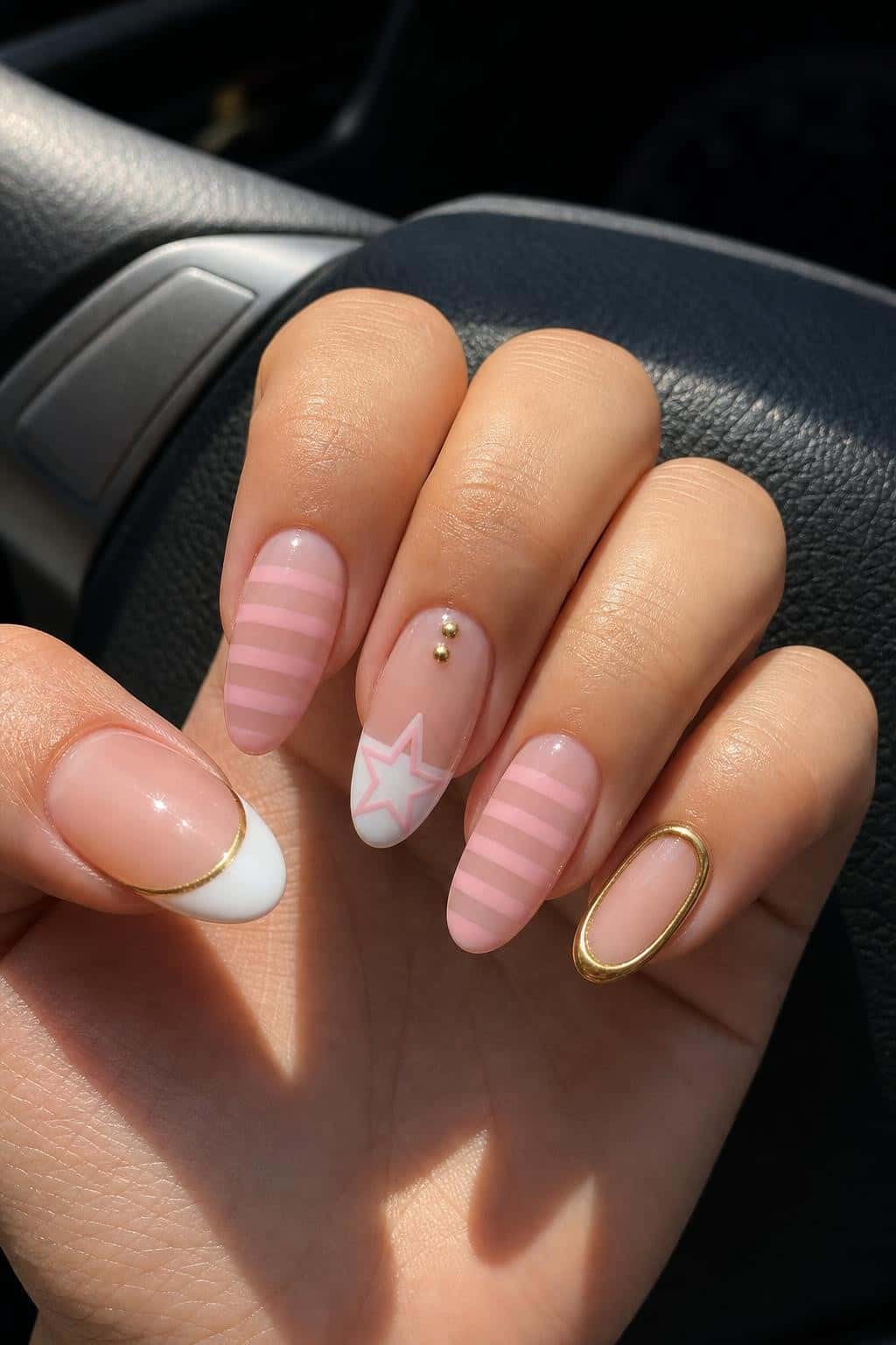 Oval nails showcasing a playful mix of pink striped, star, French tip, and gold outline designs with a glossy finish.