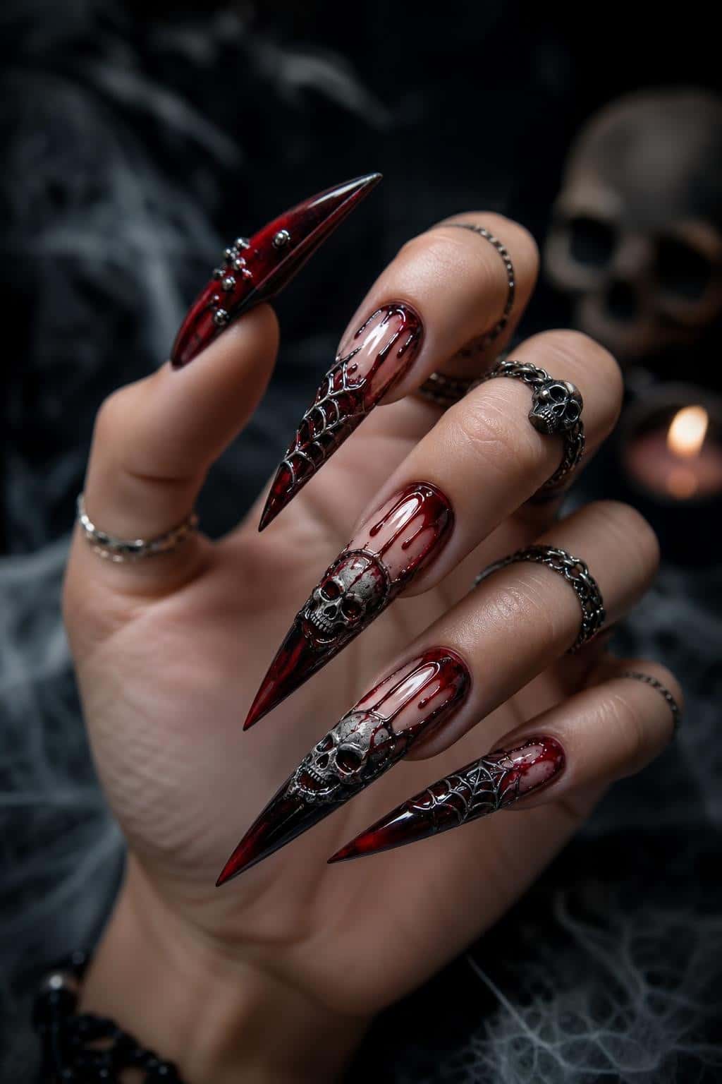 Long dark ombre stiletto nails with gothic skull art and 3D embellishments.