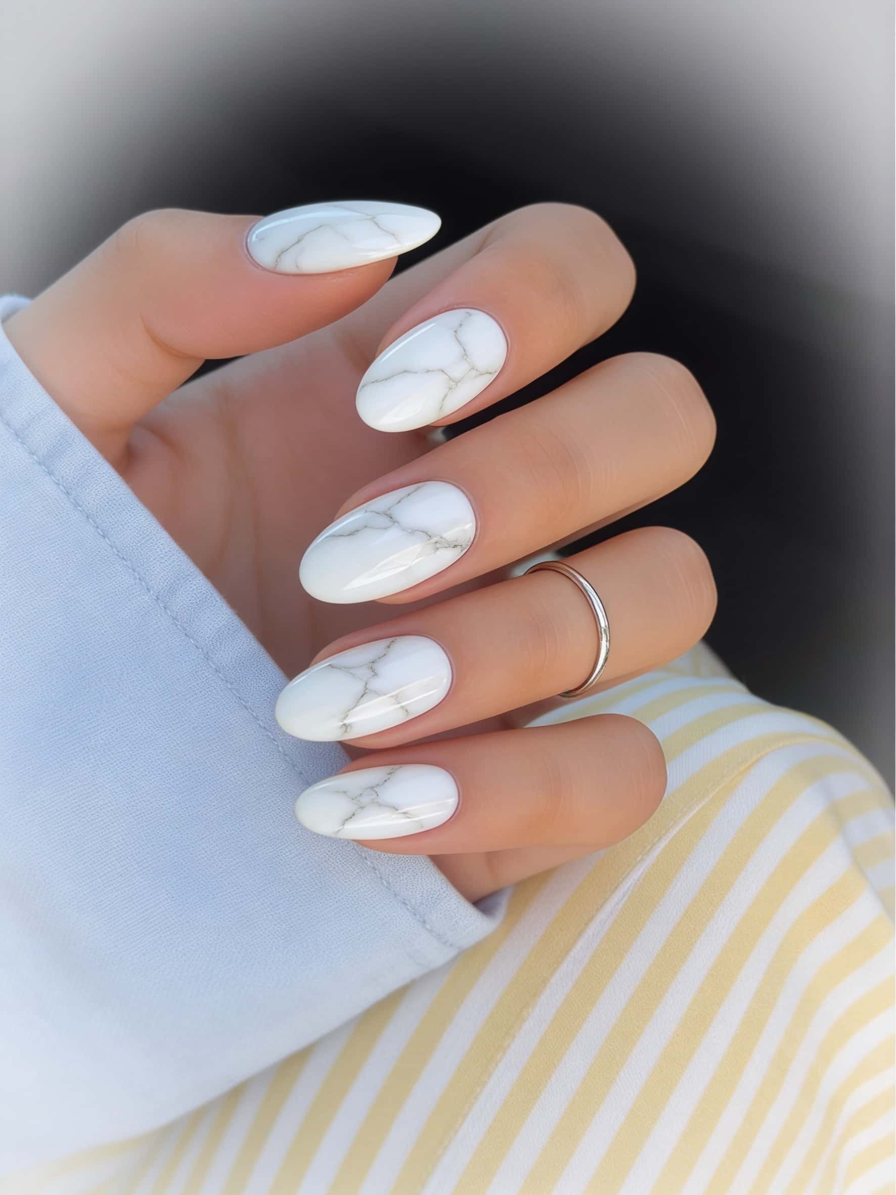Medium almond nails with a white marble design featuring subtle grey veining and a glossy finish.