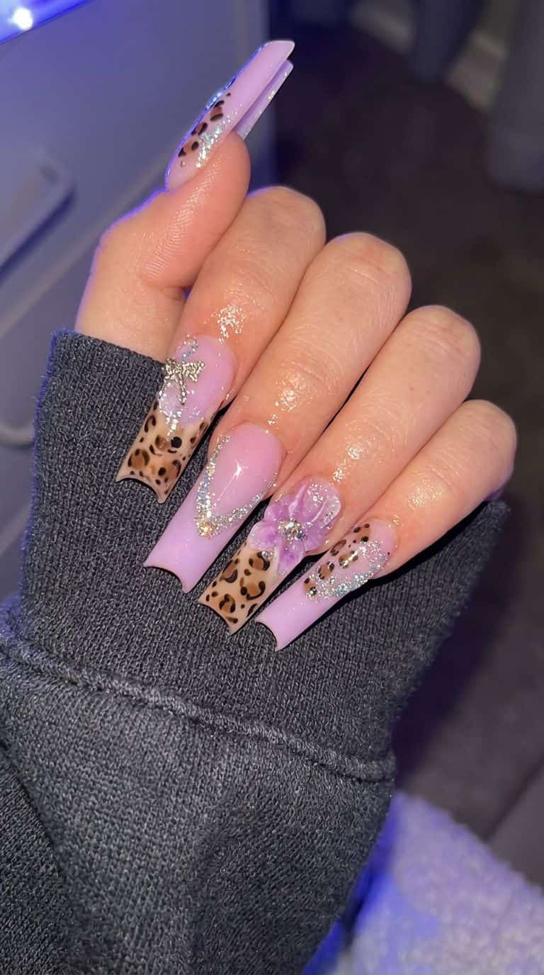 Customer's long lavender-pink ombre coffin nails with leopard print and glitter, glossy finish, posed on a dark sleeve.