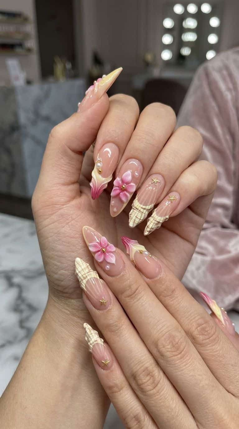 Long, glossy stiletto nails with intricate 3D floral designs, pearls, and gold studs, posed naturally outdoors.