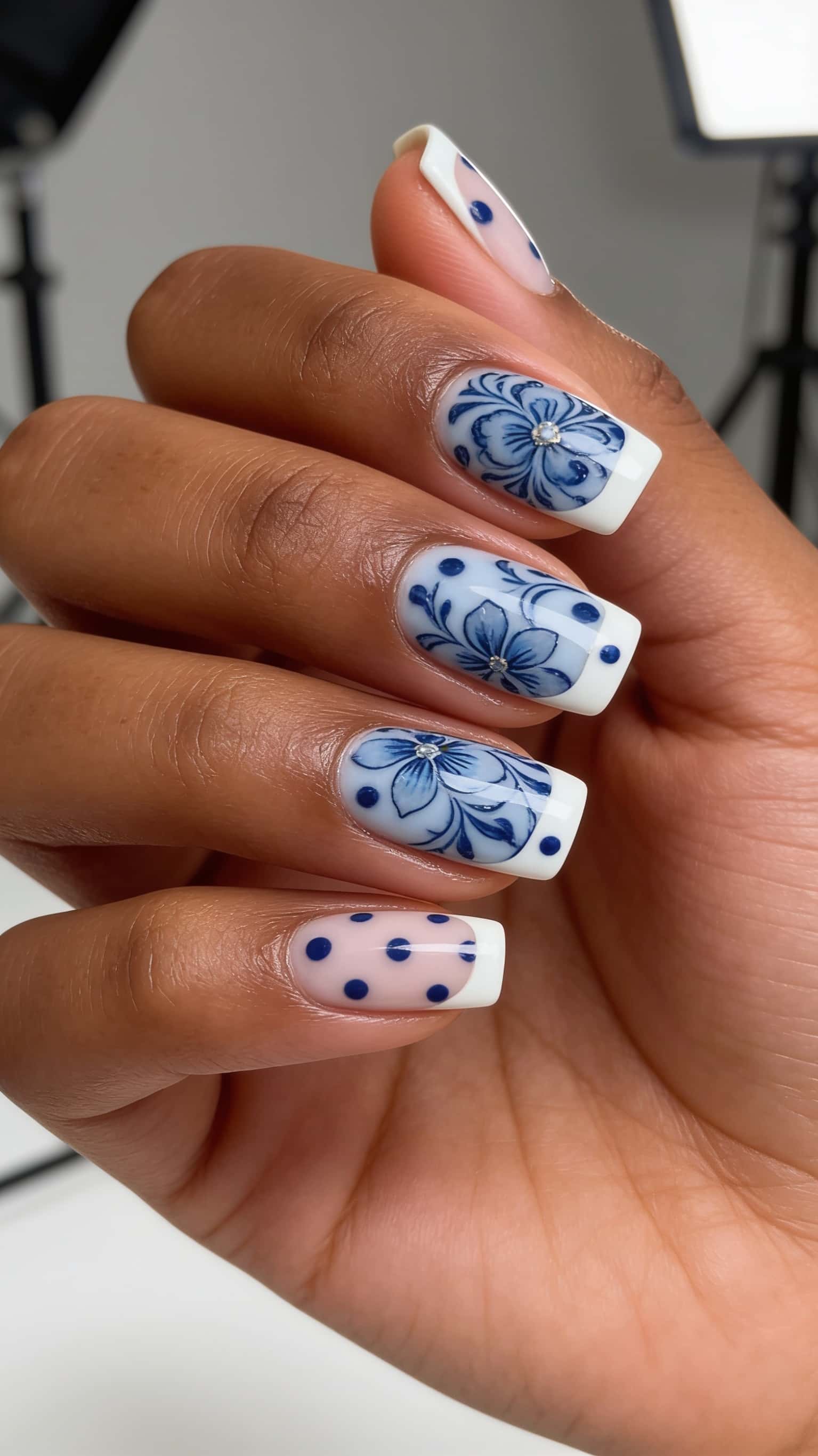 French tip nails with blue and white floral pattern and rhinestones.