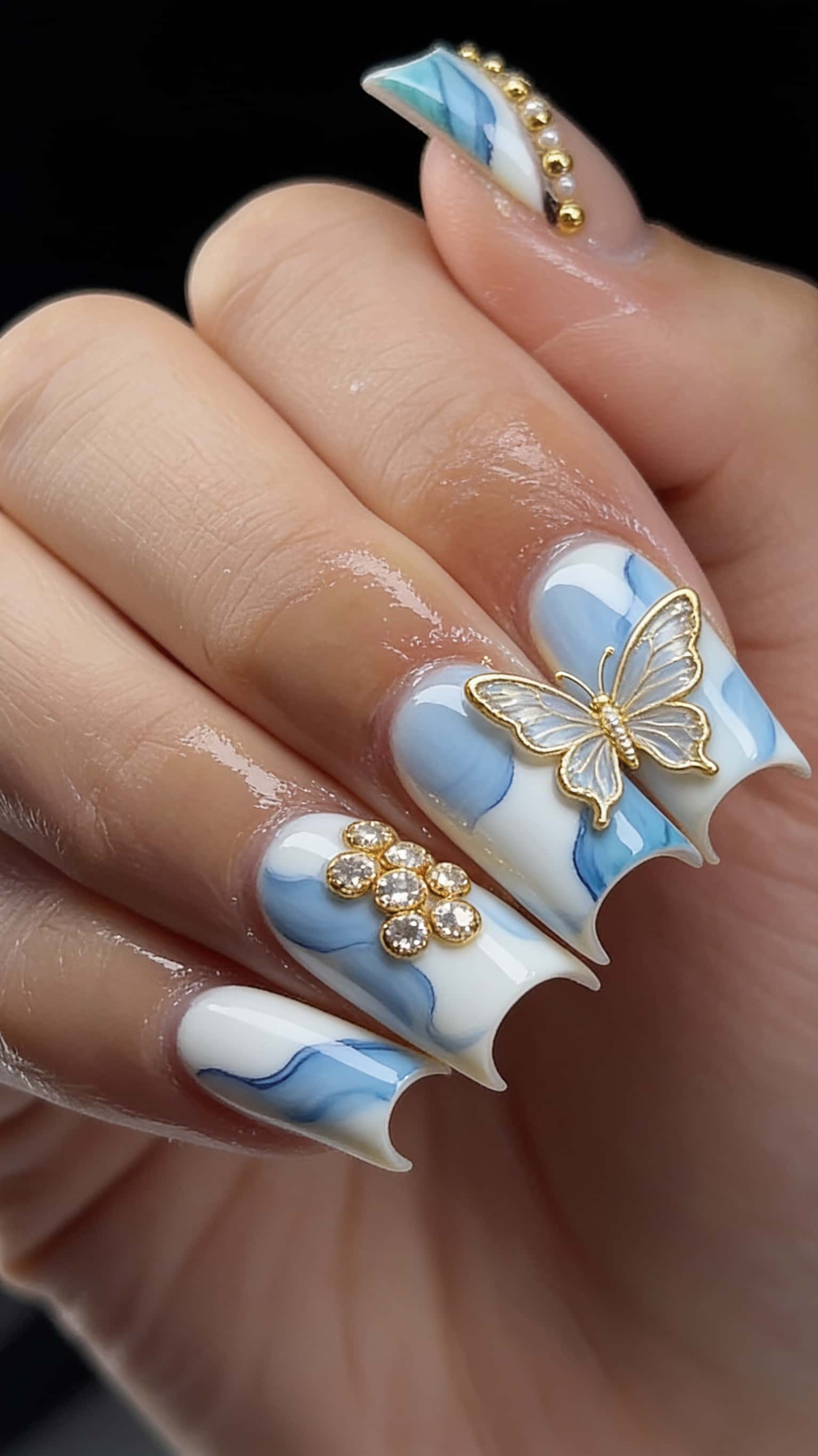 Long blue glitter stiletto nails with gold studs and rhinestones.