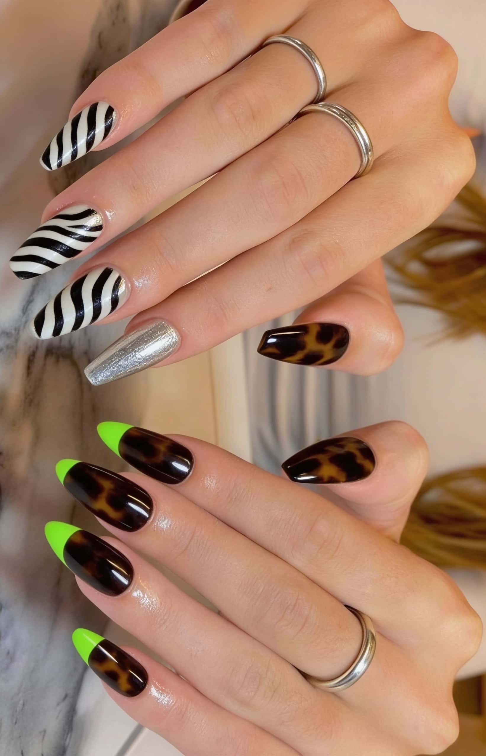 Long coffin nails with a bold mismatched design featuring zebra print, silver metallic, tortoiseshell, and neon green French tips.