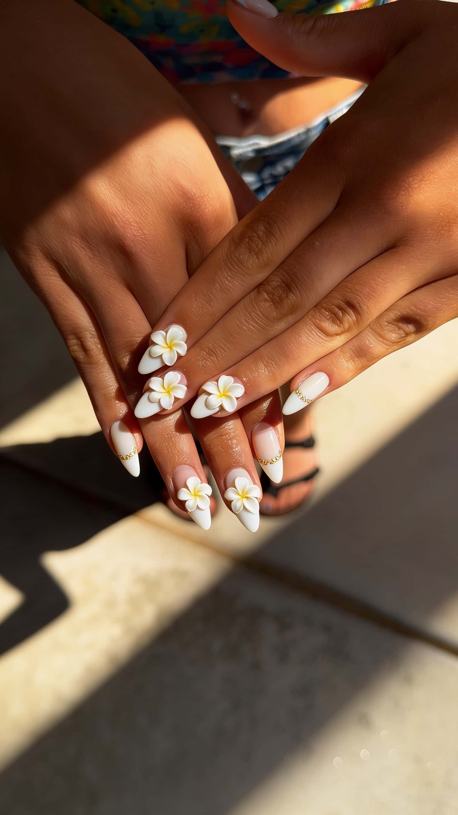 Long stiletto nails with 3D floral plumeria design and gold accents.