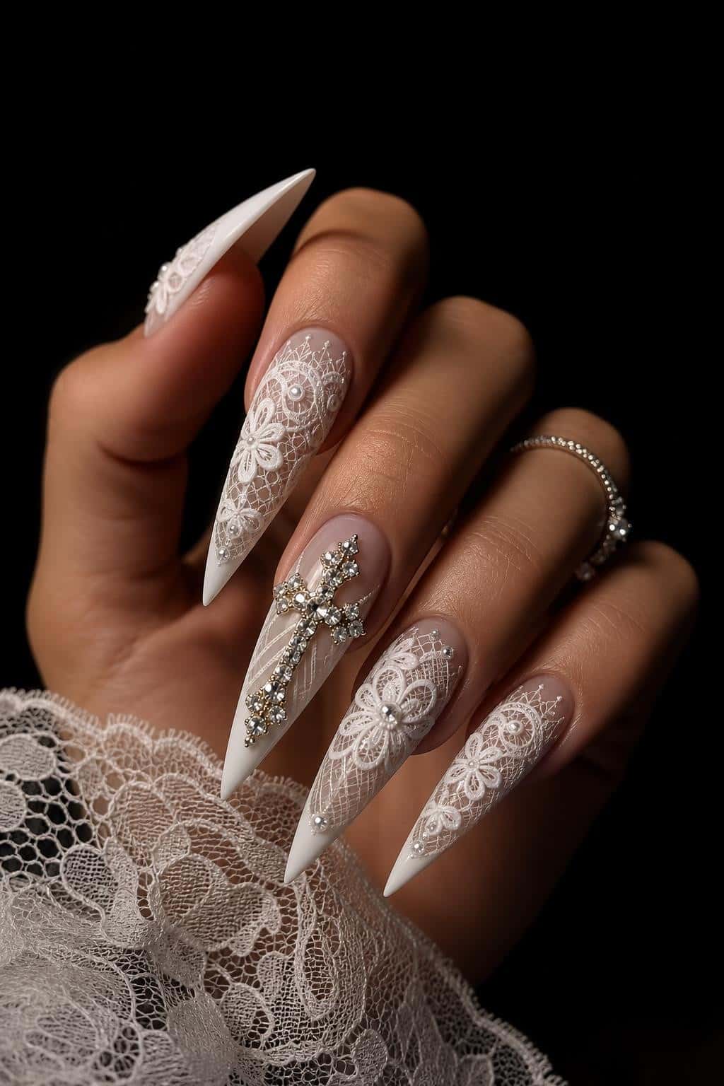 Long stiletto nails with intricate lace and floral patterns, accented with pearls and rhinestones.