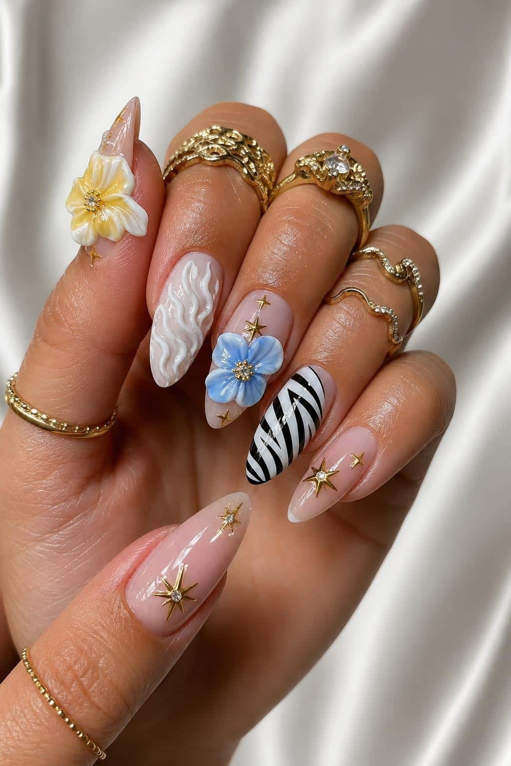 Long almond-shaped nails with 3D floral design and mixed media elements.