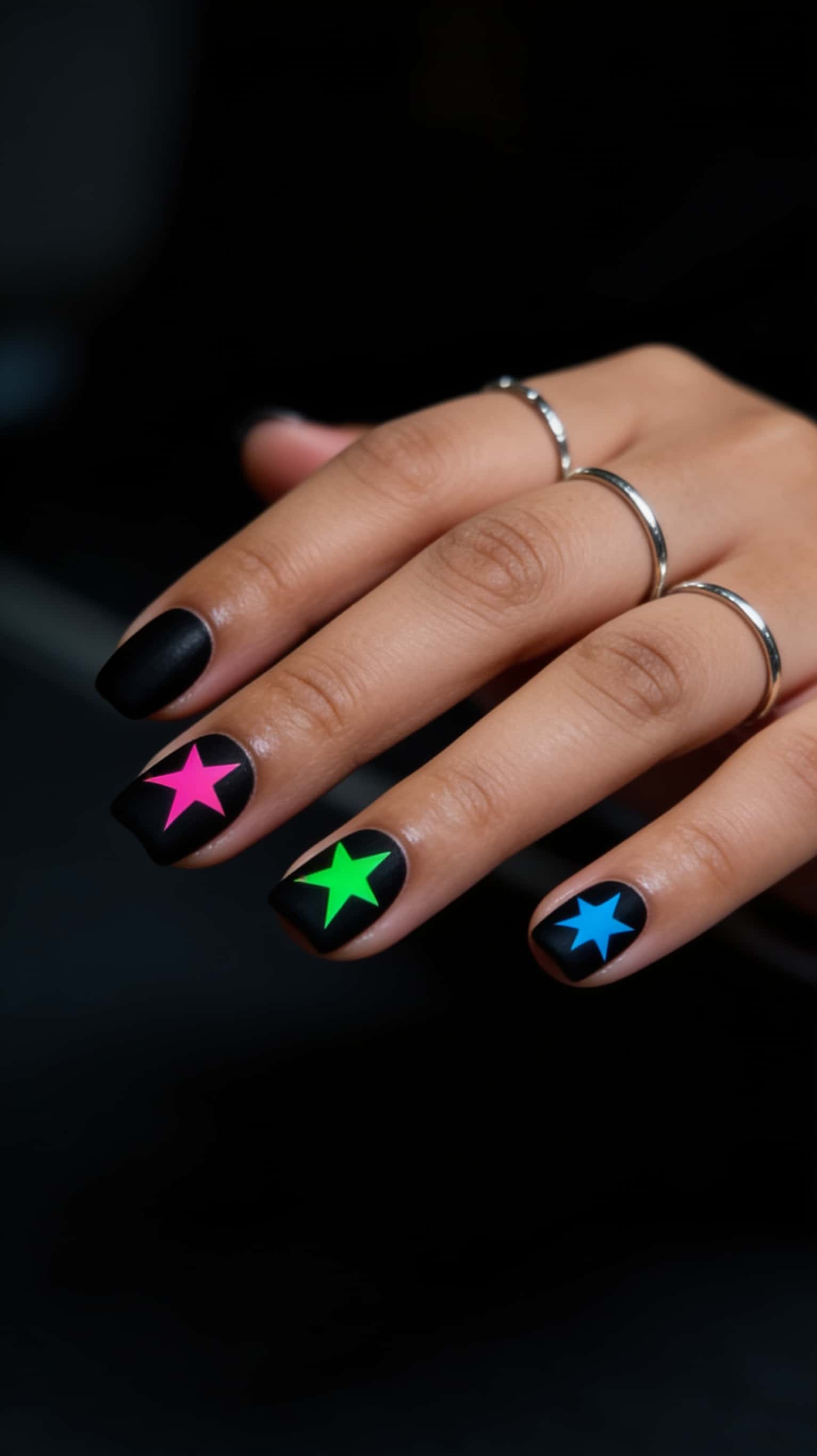 Square black matte nails with neon pink glitter stars graphic design.