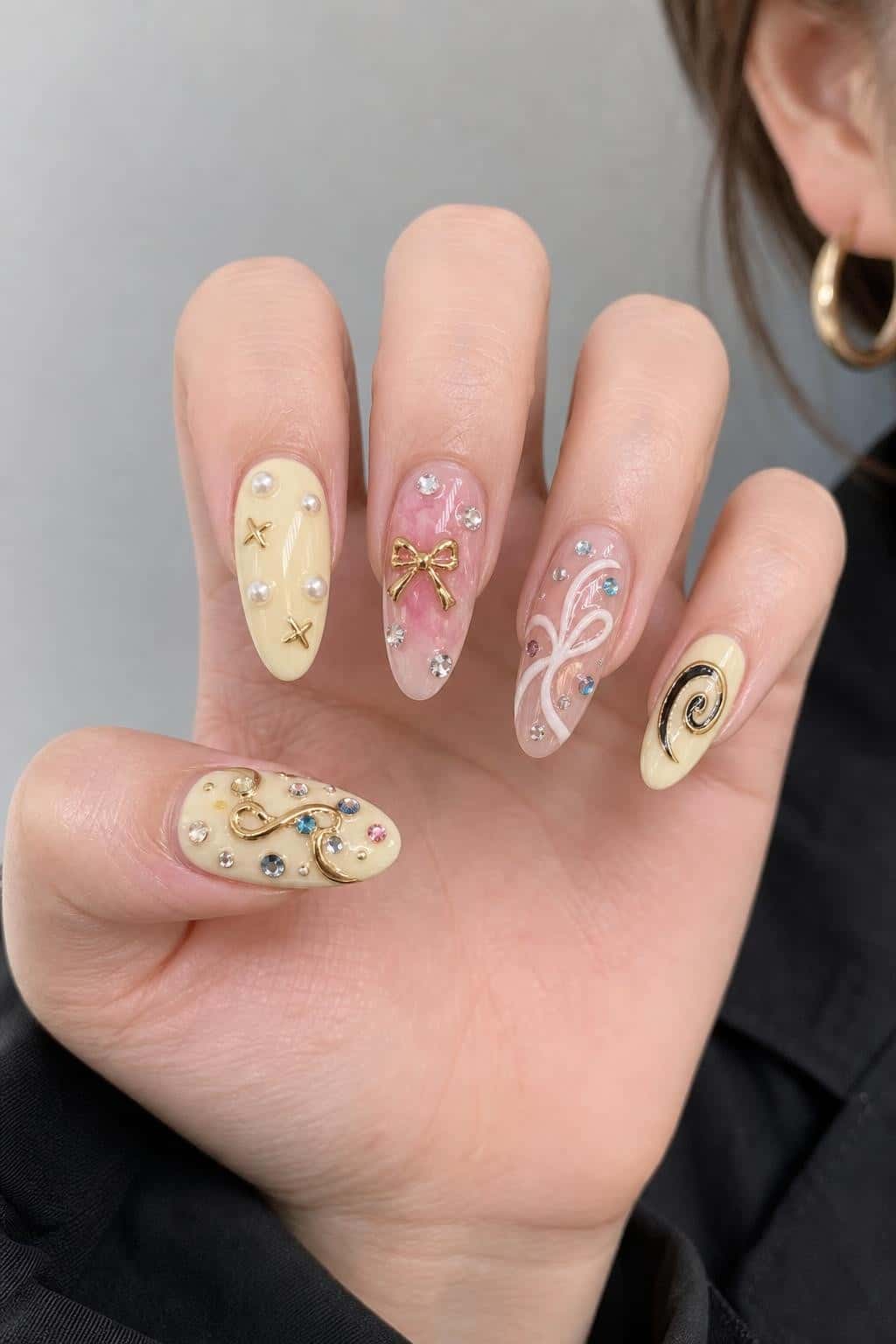 Long ornate almond nails with rhinestones, pearls, and mixed media charms.