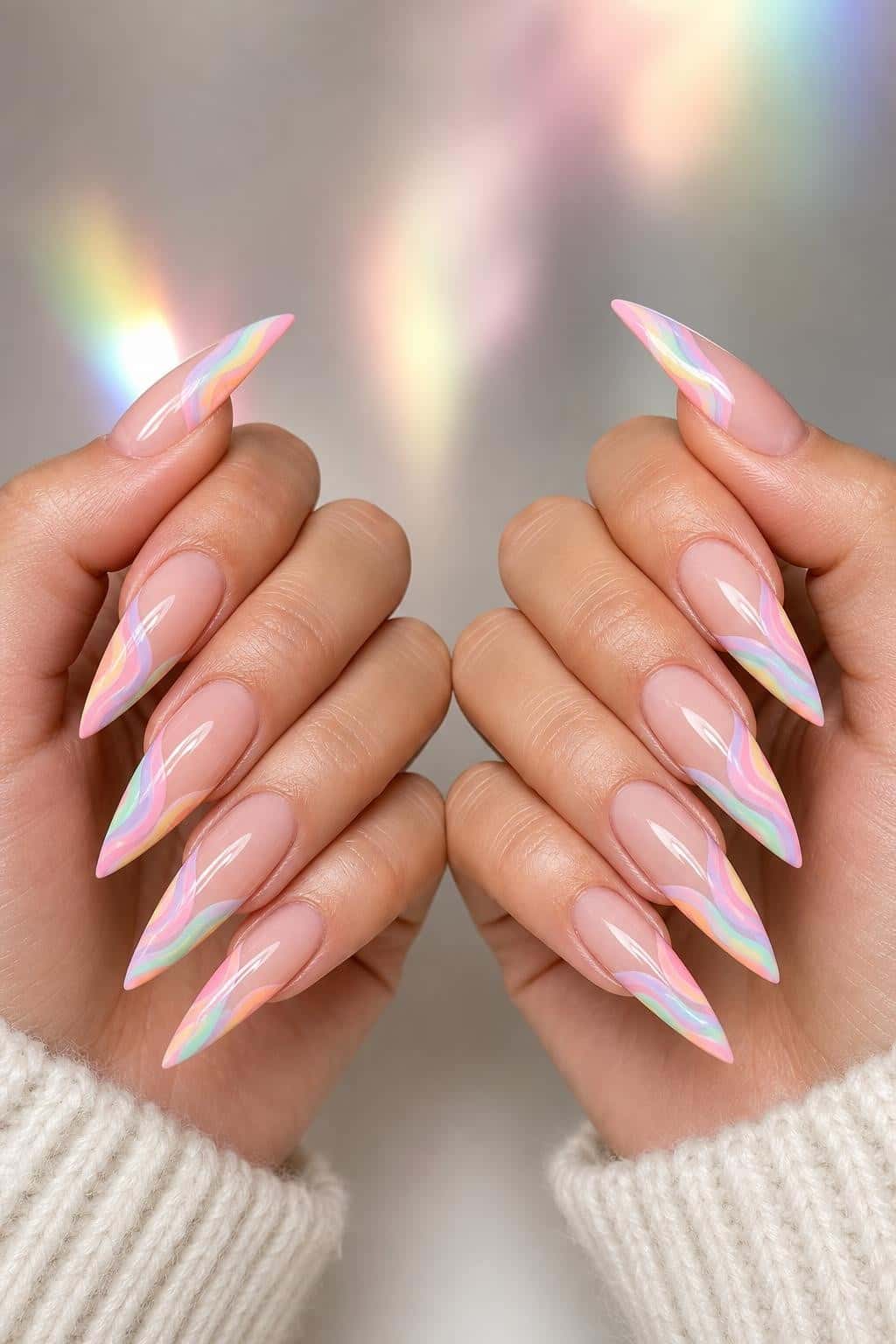 Long stiletto nails with a sheer nude base and pastel rainbow wavy French tips in a high-gloss finish.