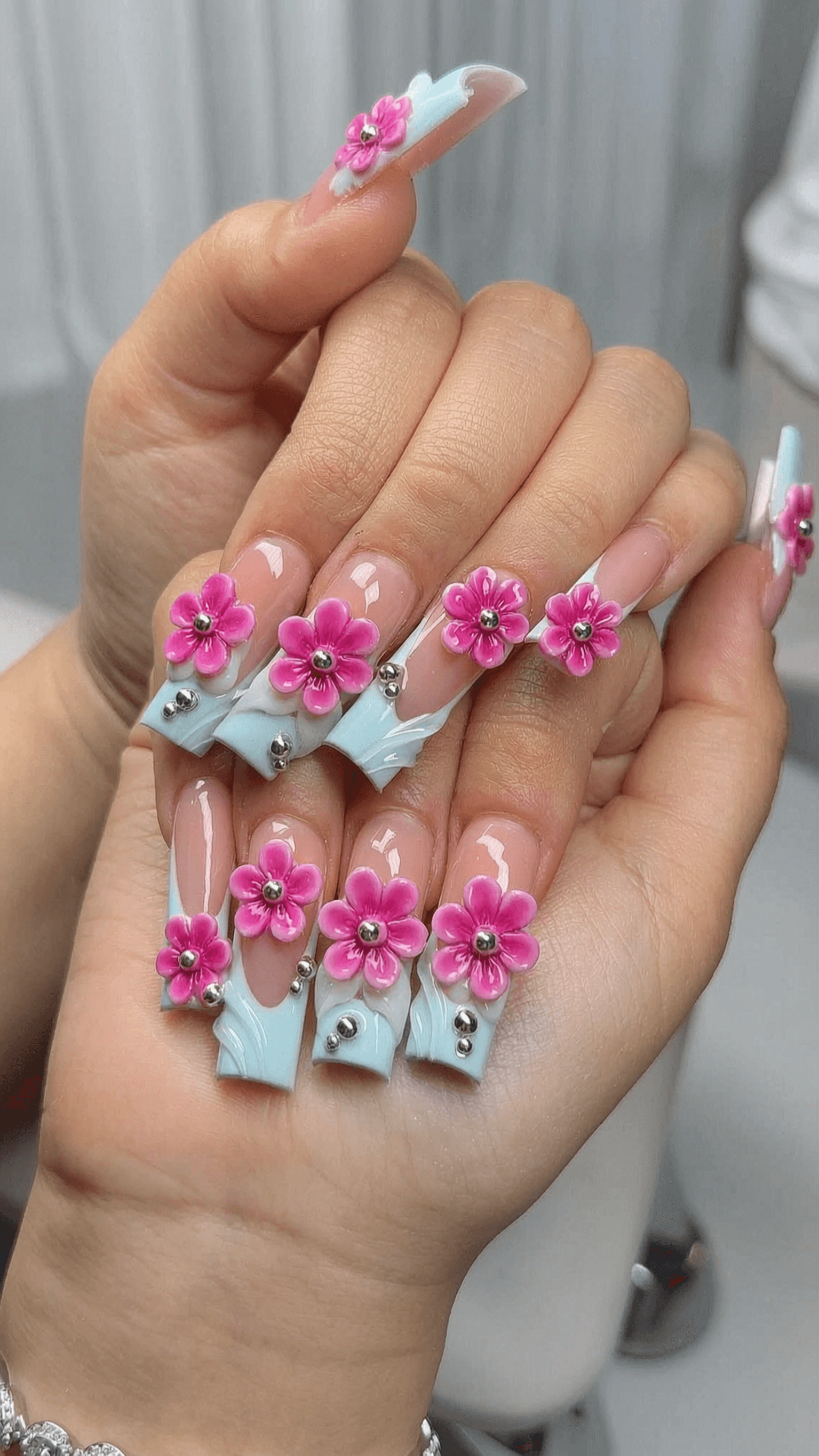 Long stiletto nails with 3D floral design in wavy pattern on nude base.