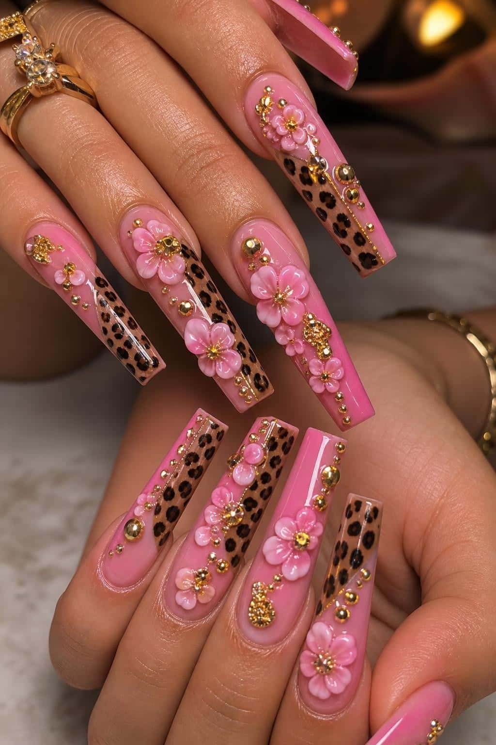 Long pink leopard stiletto nails with 3D flowers and gold embellishments.