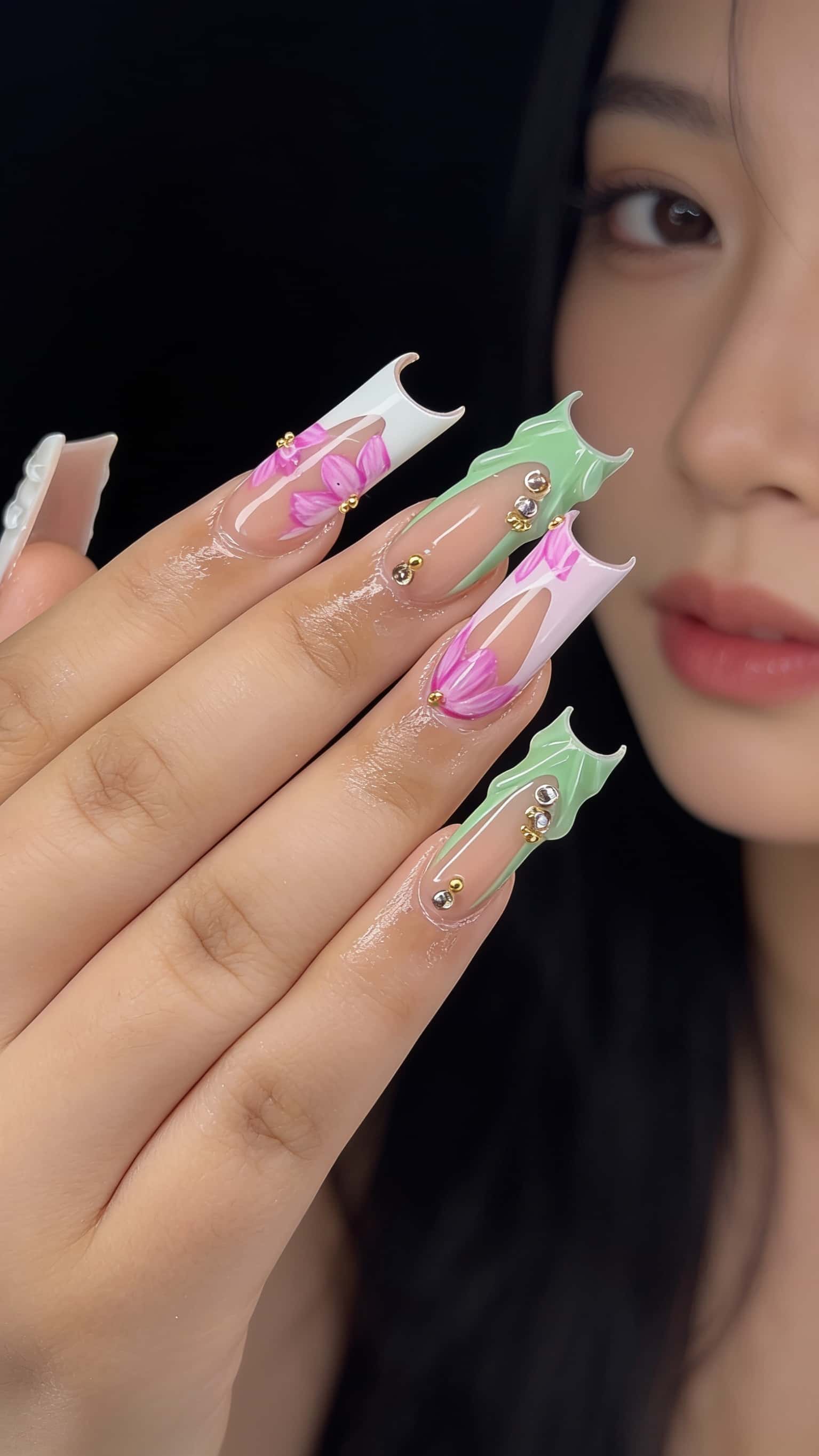 Long stiletto nails with gold studs, rhinestones, and glossy finish.