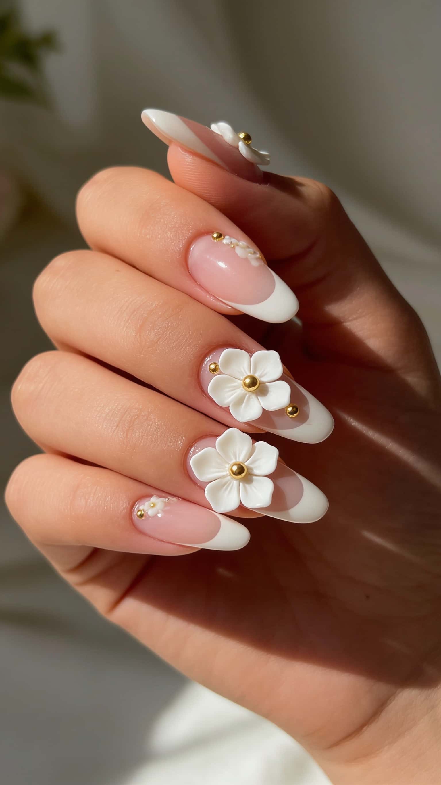 Long white almond nails with 3D floral design and gold accents.